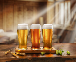 Three glasses of chilled beer on old wooden table and the sun's rays falling from the window into the interior of a village bar.