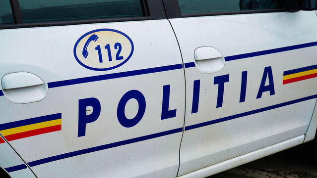 brasov romania.romanian police car.A police car displays Politia insignia and emergency contact number on its side. The vehicle is parked on a city street during bright daylight.