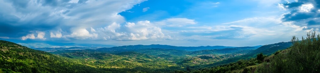 Naklejka premium Panoramic photo of beautiful green mountains in the Alps, with a blue sky and white clouds. 