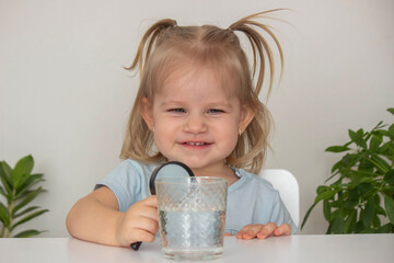 Child examines and examines water under a magnifying glass. Selective focus