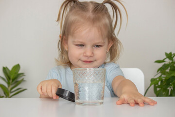 Child examines and examines water under a magnifying glass. Selective focus