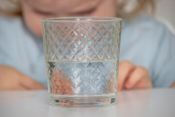 little girl drinks water from a glass. Selective focus