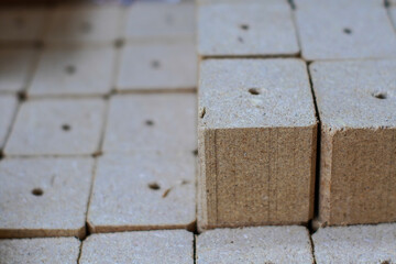 Stack of porous, light brown grow plugs or starter cubes for hydroponics or seed starting. Represents gardening supplies.