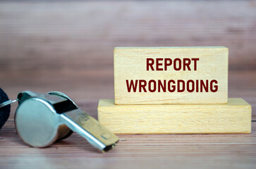 Report Wrongdoing text on wooden blocks with whistle. Whistleblow concept