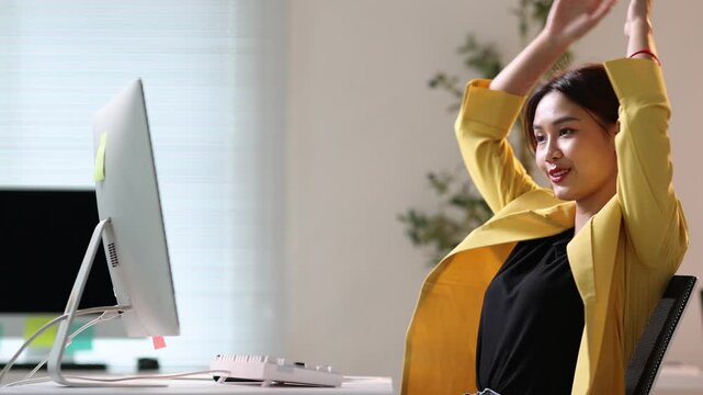 Asian businesswoman working and relaxing at office desk, enjoying a moment of relaxation in her office chair.