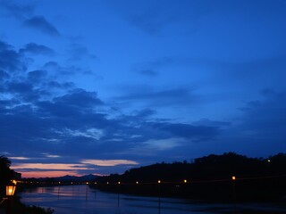 Serene river scene at sunset with lanterns floating above water, tranquil, beauty