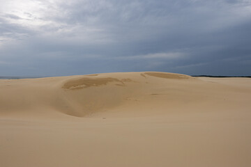 Empty sand dune with cloudy overcast sky.