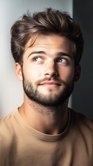 Obraz premium Thoughtful young man with stylish hairstyle gazing upwards in natural light, showcasing relaxed expression and charm