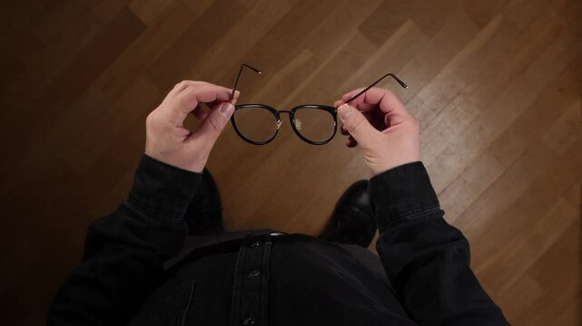 pov Man holding eyeglasses over wooden floor background