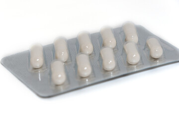 White capsules or pills in a silver blister pack. Close-up.
