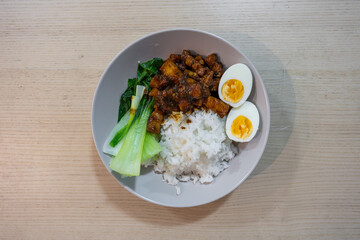 A plate of braised pork belly with bok choy, boiled eggs, and rice.