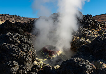 A close-up of a steaming volcanic vent in a rocky landscape.