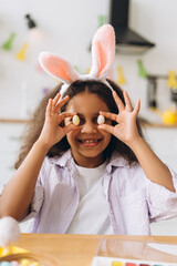 Smiling girl holding easter eggs and wearing bunny ears headband