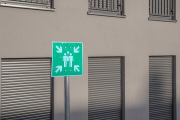Obraz premium Green assembly point sign showing escape route for evacuation