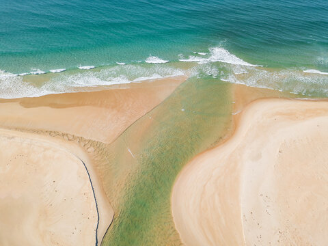 Aerial view of a river flowing over a sand bar and out into the ocean