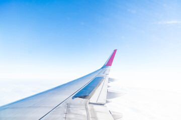 Gazing out from the cabin, a vivid view reveals the graceful curve of an aircraft wing. Lush clouds stretch endlessly below, capturing the essence of flight, adventure, and boundless freedom.