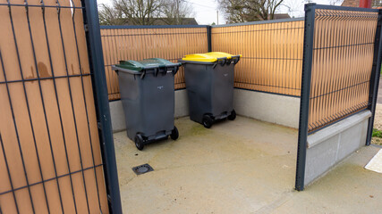 deux bacs de poubelles pour déchets ménagers et tri sélectif dans un box extérieur