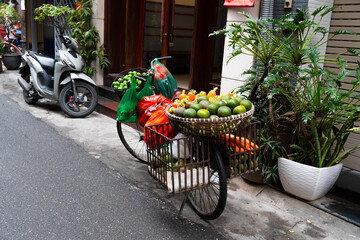 Vibrant mandarin oranges and limes on a bicycle cart create a festive atmosphere. The street market...