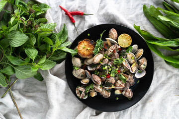 Garlic clams garnished with fresh herbs and chili, featuring vibrant colors and textures.
