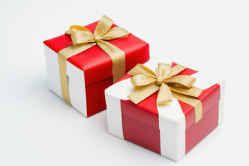 Obraz premium Two beautifully wrapped gift boxes, red and white with gold ribbons, perfect for celebrations. isolated on white background.