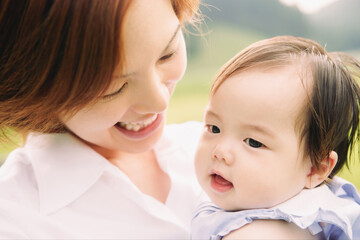 母親に抱っこする生後7ヶ月の女の子　公園