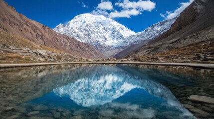 Majestic Snow-Capped Mountain Reflecting in a Calm Lake Under a Bright Blue Sky