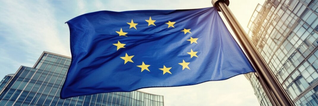 A blue and yellow flag with stars on it is flying in front of a building. The flag is on a pole and is in the air