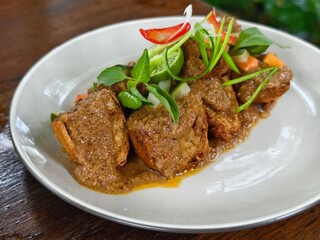 A traditional Indonesian dish featuring fried tofu with a rich peanut sauce, garnished with fresh vegetables and lime