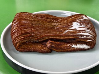 A chocolate pain Suisse with chocolate layers, a flaky texture, and powdered sugar on top