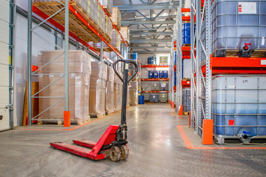 Warehouse distribution center. Logistic storage interior. Empty pallet jack between warehouse racks. Warehouse with IBC with containers. Logistics center inside hangar. Fulfillment center from inside