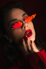 Young Woman In Red Suit With Red Lips And Sunglasses Posing On The Black Background