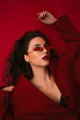 Young Woman In Red Suit With Red Lips And Sunglasses Posing On The Red Background