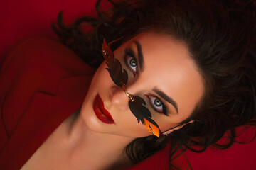 Young Woman In Red Suit With Red Lips And Sunglasses Posing On The Red Background