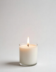 Lit White Candle with Green Leaves on a Minimal Background