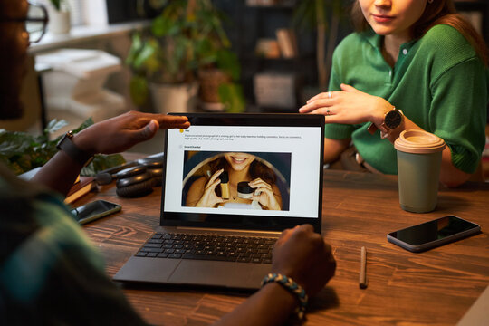 Colleagues sitting at table and planning content with vlm model on laptop in team