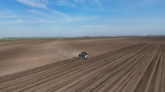 Areal shot of tractor plowing a field. Drone shot of sunny day and agriculture