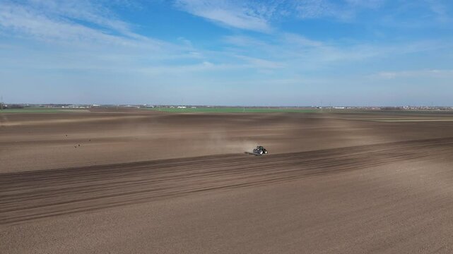 Drone aprotching shot of tractor plowing a field. Drone shot of sunny day and agriculture