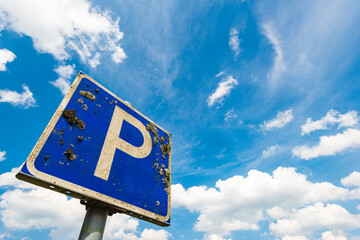 Parking sign against a bright blue sky with scattered clouds in Sweden's vibrant landscape