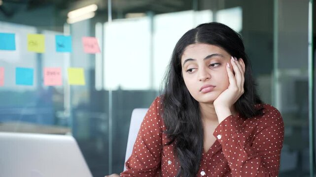 Young businesswoman is bored sitting at workplace in business office. Exhausted female employee is tired working with laptop. A sleepy worker yawns, procrastinates, gets distracted. Fatigue. Close up