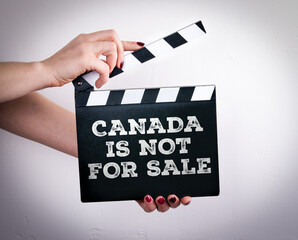 Obraz premium CANADA IS NOT FOR SALE concept. Female hands holding movie clapper