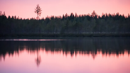 Reflection of sunset colours on the surface of a lake in the forests of eastern Finland on a summer night
