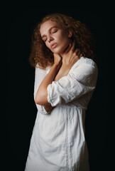 Studio portrait of cute young woman in white dress against black background
