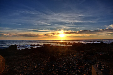 Falling sun descends gently glowing to the horizon over the Pacific Ocean in Cambria on coast of California