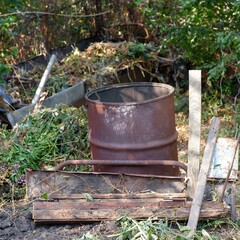 Obraz premium An overgrown junkyard with an old rusty barrel and old wooden planks