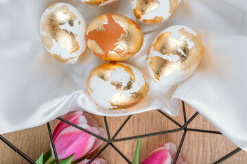 Gold Easter eggs in a basket with pink tulips, top view. Easter backgorund.