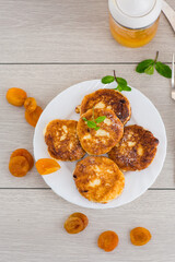 Fresh cottage cheese pancakes with pieces of dried apricots and a leaf of mint