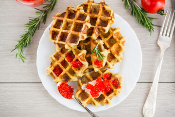 Potato waffles with red caviar on a wooden table