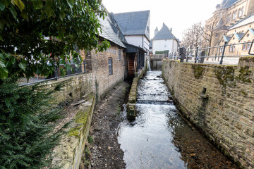 M&uuml;hlengraben mit M&uuml;hlenrad. Links das M&uuml;hlenhaus ,rechts eine hohe alte Mauer. 