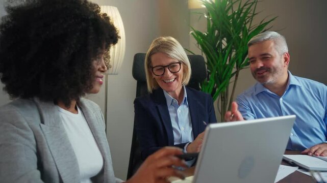 Three busy happy middle aged professional business man and two women executive leaders team using laptop working on computer at work desk having conversation on financial project at meeting in office.