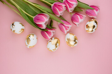 Easter gold eggs with tulips on a pastel pink background.
